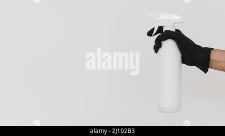 Hand mit Handschuh, der die Desinfektionsflasche mit Kopierraum hält Stockfoto