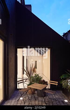 Kleiner Innenhof im obersten Stockwerk mit Sitzgelegenheiten im Freien. Symes Mews, London, Großbritannien. Architekt: PH+ Architects, 2020. Stockfoto