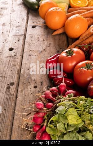 Hochwinkelansicht von Rettich, Pfeffer und Früchten auf einem Holztisch Stockfoto