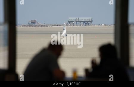 St. Peter Ording, Deutschland. 21. März 2022. Ein Strandsegler rast über den Nordseestrand, während die Gäste im Restaurant Noah's Ark sitzen. Kredit: Marcus Brandt/dpa/Alamy Live Nachrichten Stockfoto