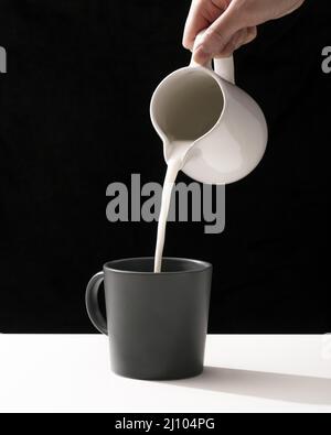 Vorderansicht Milch von Hand in den Becher gießen Stockfoto