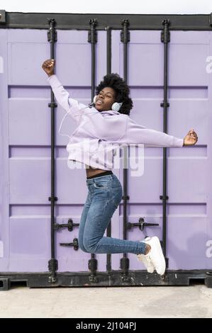 Portrait junge Frau mit Kopfhörer springen 2 Stockfoto