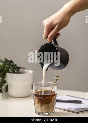 Person, die ein Glas mit Sahnekaffee aus Stockfoto