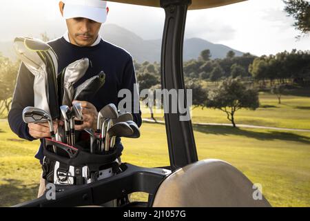 Vorderansicht Mann Putting Clubs Golfwagen Stockfoto