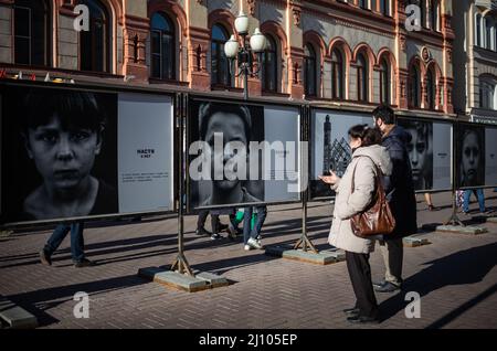 (220321) -- MOSKAU, 21. März 2022 (Xinhua) -- die Menschen sehen sich die Arbeiten der Fotoausstellung "Look in the Eyes of Donbass" in der Arbat Street in Moskau, Russland, am 20. März 2022 an. (Xinhua/Bai Xueqi) Stockfoto