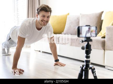 Hübscher Mann, der persönliches Training zuhause aufzeichnet Stockfoto