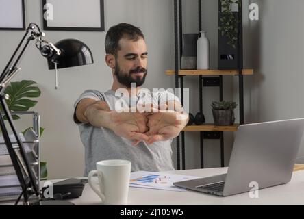 Mann streckt seine Arme, während er von zu Hause aus arbeitet Stockfoto