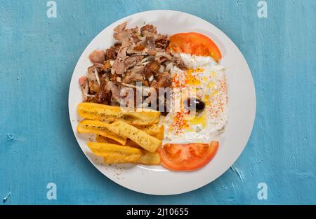 Griechisches Gyro-Gericht mit Lammfleisch mit Zwiebeln, Pommes Frites und Tzaziki-Sauce mit Tomate Stockfoto
