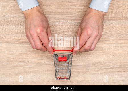 Geschäftsmann schiebt den Spielzeugwagen auf den hölzernen Hintergrund Stockfoto