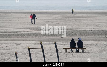 St. Peter Ording, Deutschland. 21. März 2022. Passanten genießen das sonnige Wetter am Nordseestrand. Kredit: Marcus Brandt/dpa/Alamy Live Nachrichten Stockfoto