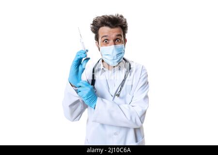 Bereit für die Injektion. Männlicher junger Arzt mit Stethoskop und Gesichtsmaske auf weißem Studiohintergrund. Sieht traurig, ernst aus. Konzept des Gesundheitswesens und Stockfoto