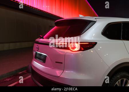 Kiew, Ukraine - 4. Dezember 2021: Der neue Mazda CX-9 in der Nähe der beleuchteten roten Mauer bei Nacht Stockfoto