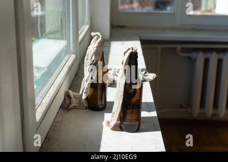 Glasflasche, gefüllt mit Benzin, einem sogenannten Molotow-Cocktail, auf dem Fenster im Haus Stockfoto
