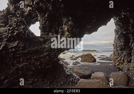 Felssäulen, die aus basaltischer Lava in Küstenklippen am Strand von Reynisfjara in der Nähe von Vik, Südküste Islands, entstanden sind. Stockfoto