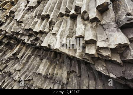 Felssäulen, die aus basaltischer Lava in Küstenklippen am Strand von Reynisfjara in der Nähe von Vik, Südküste Islands, entstanden sind. Stockfoto