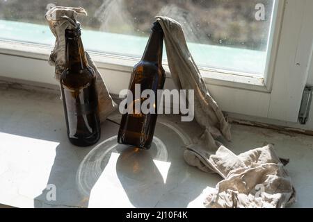 Glasflasche, gefüllt mit Benzin, einem sogenannten Molotow-Cocktail, auf dem Fenster im Haus Stockfoto