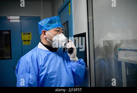 (220321) -- TIANJIN, 21. März 2022 (Xinhua) -- Geng Tian kommuniziert mit seinem Kollegen in einem Labor über Walkie-Talkie auf einer nukleardiagnostischen Testbasis im nordchinesischen Tianjin, 19. März 2022. Geng Tian, 49, ist Arzt des Ersten Krankenhauses in Tianjin. Während des jüngsten Wiederauflebens von COVID-19 ist Geng für die Durchführung von Nukleinsäuretests an einer lokalen Testbasis verantwortlich, die über eine tägliche Testkapazität von über 15.000 Röhrchen verfügt. Um den reibungslosen Betrieb mit höherer Geschwindigkeit zu gewährleisten, arbeitet Geng täglich rund um die Uhr in einem sauberen Korridor mit einer Länge von 30 Metern im Sockel. Sein Notbehelf Stockfoto