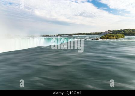 Fließendes Wasser in Niagara fällt an einem teilweise bewölkten Herbsttag. Kraft in der Natur. Stockfoto