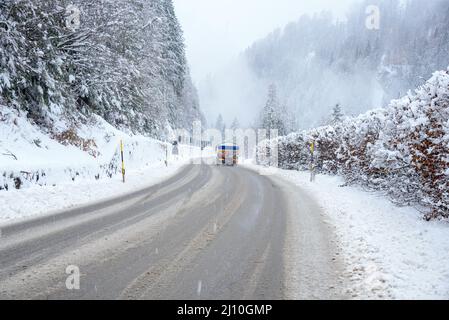 Tankwagen auf einer verschneiten Bergstraße bei starkem Schneefall im Winter Stockfoto