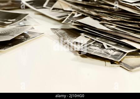 Haufen alter schwarz-weißer Familienfotos auf weißem Tisch, Erinnerungen und Nostalgie Stockfoto