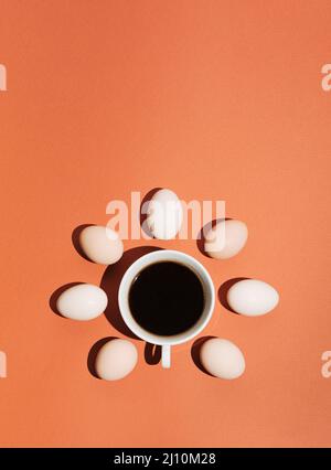 Kreatives Konzept mit einer Tasse Kaffee, Schatten und Eiern auf pastellbraun-orangefarbenem Hintergrund. Minimaler Plan-Lay-Mockup. Stockfoto