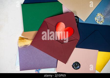 Rotes Herz in einem Umschlag. Viele bunte Umschläge. Umschläge mit Wachs versiegelt. Korrespondenz, valentinstag-Konzept. Stockfoto
