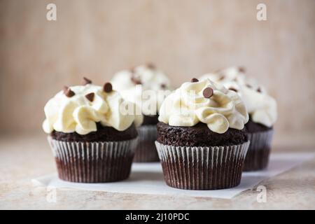 Reichhaltige Schokoladen-Cupcakes mit Schlagsahne und Schokoladenstückchen. Stockfoto