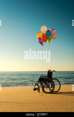 Rollstuhl mit gefesselten Ballon am Strand Stockfoto