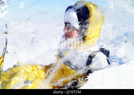 Mädchen schaut durch eine transparente Eisscholle am baikalsee Stockfoto