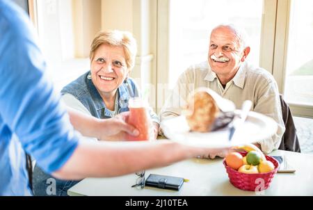 Der Kellner serviert ein Seniorenpaar, das im veganen Restaurant isst - Rentner und Frauen auf aktiven älteren Menschen, die Spaß haben - Happy Retirement Concept mit reifer ppe Stockfoto