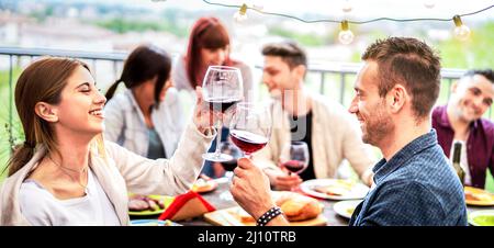 Glückliches Paar, das beim Abendessen auf dem Bauernhof Spaß hat, Wein zu trinken - Junge Freunde essen gemeinsam Barbeque-Brunch im Restaurant - Essen im Lebensstil con Stockfoto