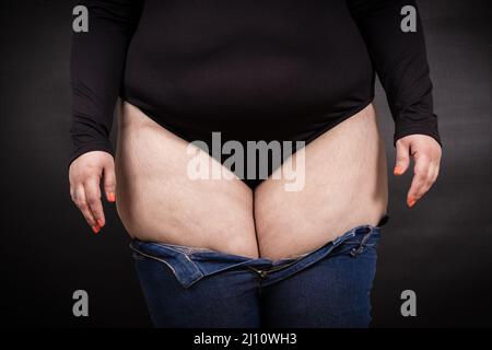 Fette Frau in Jeans auf schwarzem Hintergrund Stockfoto