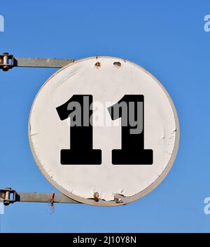 Rundes Straßenbanner mit der Nummer 11 im Hintergrund des Himmels. Stockfoto