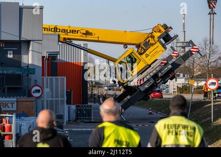 Pentling, Deutschland. 21. März 2022. Ein LKW-Kran mit seinem Ausleger fiel auf das Dach eines Supermarkts. Nach ersten Polizeiberichten wurde bei dem Unfall niemand verletzt. Das Gebäude wurde evakuiert. Quelle: Armin Weigel/dpa/Alamy Live News Stockfoto