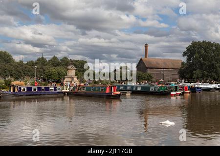 Touristen genießen es, die farbenfrohen Schmalboote zu bewundern, die in der Nähe einer Shakespeare-Statue in Stratford-upon-Avon festgemacht sind. Stockfoto