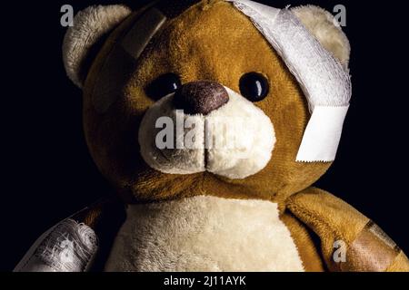 Trauriger, verletzter Teddybär, der medizinische Hilfe benötigt. Konzeptuelles Bild von Gewalt oder Kindesmissbrauch Stockfoto