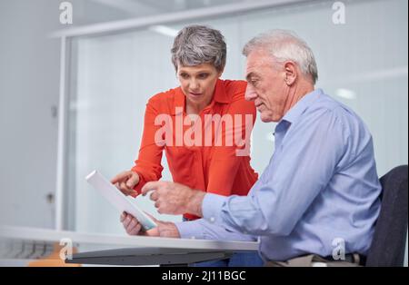 Planung für das nächste Geschäftsjahr. Aufnahme von zwei reifen Geschäftskollegen, die mit einem digitalen Tablet sitzen und über ihre Arbeit diskutieren. Stockfoto
