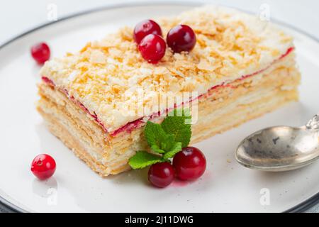 Stück Kuchen Napoleon auf weißem Teller. Russische Küche, mehrschichtiger Kuchen mit Konditorcreme, Nahaufnahme. Stockfoto