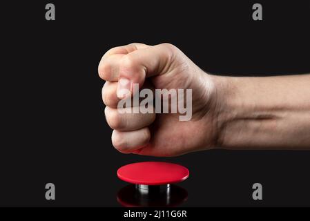 Die Hand eines Mannes drückt einen großen roten Knopf. Rote Taste auf dunklem Hintergrund. Die Drohung mit nuklearen oder chemischen Massenvernichtungswaffen. Rakete Stockfoto