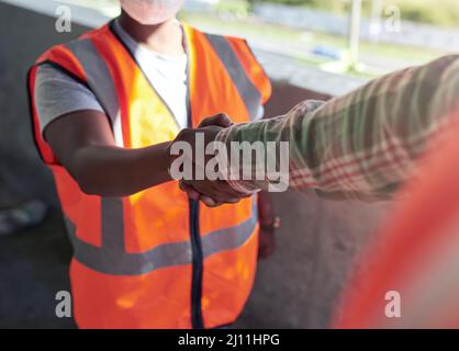 Wir arbeiten zusammen, um noch besser zu bauen. Aufnahme von zwei Bauherren, die sich auf einer Baustelle die Hände schüttelten. Stockfoto