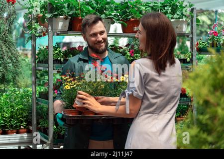 Mitarbeiter hilft weiblichen Kunden bei der Arbeit im Gartencenter Stockfoto