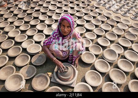 Arbeiter stellen Tontöpfe als eine Form von Töpferei her, um sie auf einem Markt in Brahmanbaria, Bangladesch, zu verkaufen. Die Arbeiter sammeln Ton aus dem Boden, Formen ihn dann mit den Händen, trocknen ihn in der Sonne, feuern in die Öfen und bemalen schließlich die fertige Keramik. Wie viele andere traditionelle Handwerksbetriebe steht auch die Töpferei in Bangladesch vor dem Aussterben. Ein Beruf, der hauptsächlich den Menschen der Hindu-Töpfergemeinschaft gehört, ändern die Handwerker dieses Handels ihre Lebensgrundlage. Der Grund für das Verlassen des Töpferhandwerks sind viele: Hohe Materialkosten, der immer verlorene rac Stockfoto