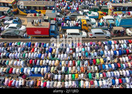 Muslimische Anhänger beten inmitten einer belebten Straßenkreuzung, was den Verkehr zum Stillstand bringen würde, in Tongi, Dhaka, Bangladesch während Bishwa Ijtema, einer der größten islamischen religiösen Versammlungen, die jährlich stattfinden. Dedizierte Gebetsstätten reichen nicht aus, um diese große Anzahl von Menschen zu bewältigen, so dass eine große Anzahl von Menschen nach Tongi, der Hauptstraße von Dhaka, kommt. Während dieser Zeit werden alle Bodentransporte und Fußgängerübergänge ausgesetzt. Bangladesch. Stockfoto