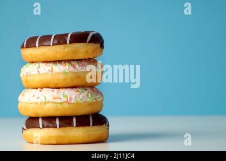 Leckere, frische Donuts, bunt und mit Schokolade, liegen nebeneinander, übereinander Stockfoto