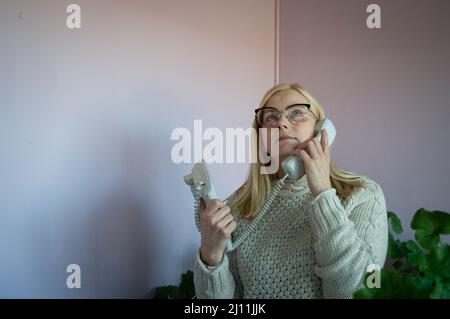 Frau, die über ein analoges altes Telefon im Büro spricht Stockfoto