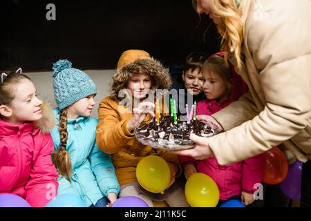 Dnipro, Ukraine - 21. März 2022: Kindergeburtstag in einem Bombenhaus während eines Luftangriffs. Kinder schmecken Geburtstagskuchen. Stockfoto