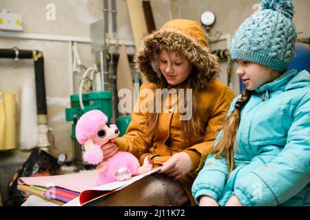 Dnipro, Ukraine - 21. März 2022: Zwei Mädchen spielen während eines Luftangriffs und sitzen in einem Tierheim. Stockfoto