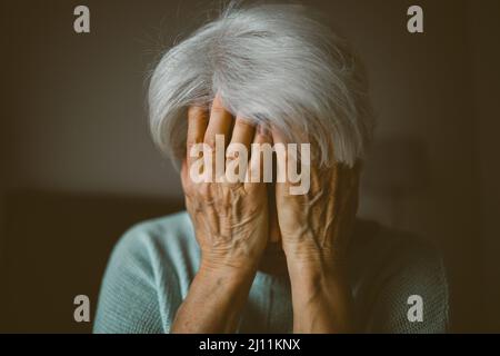 Ältere Frau für Gesicht mit ihren Händen Stockfoto