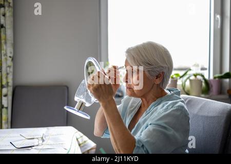 Ältere Frau, Die Vor Dem Spiegel Make-Up Macht Stockfoto
