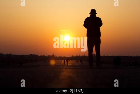 Berlin, Deutschland. 21. März 2022. Ein Mann fotografiert den Sonnenuntergang auf dem Tempelhofer Feld. Quelle: Hauke Schröder/dpa-Zentralbild/ZB/dpa/Alamy Live News Stockfoto